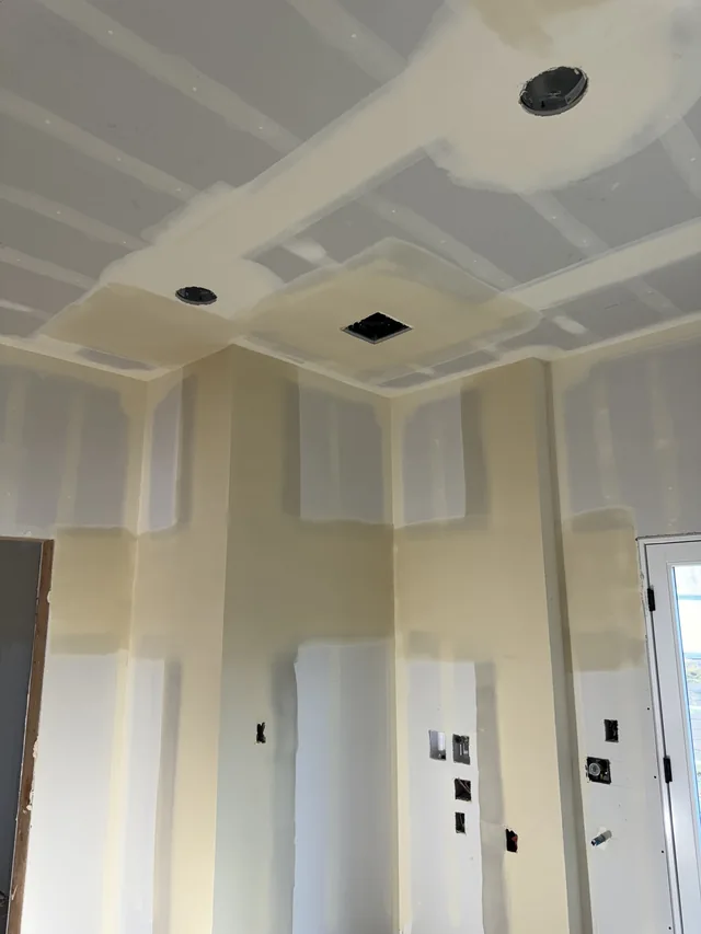 Taped drywall seams across a ceiling and adjoining walls.
