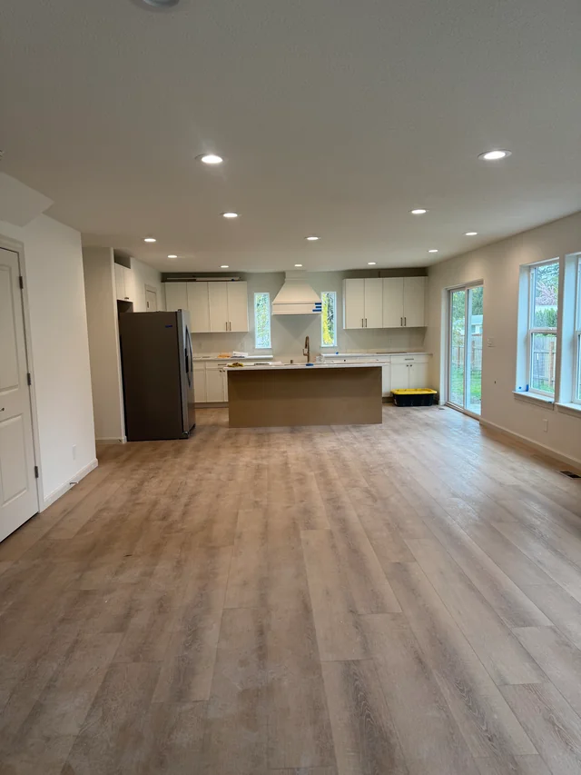 Finished walls and a textured ceiling with recessed lights above an open living area and kitchen.