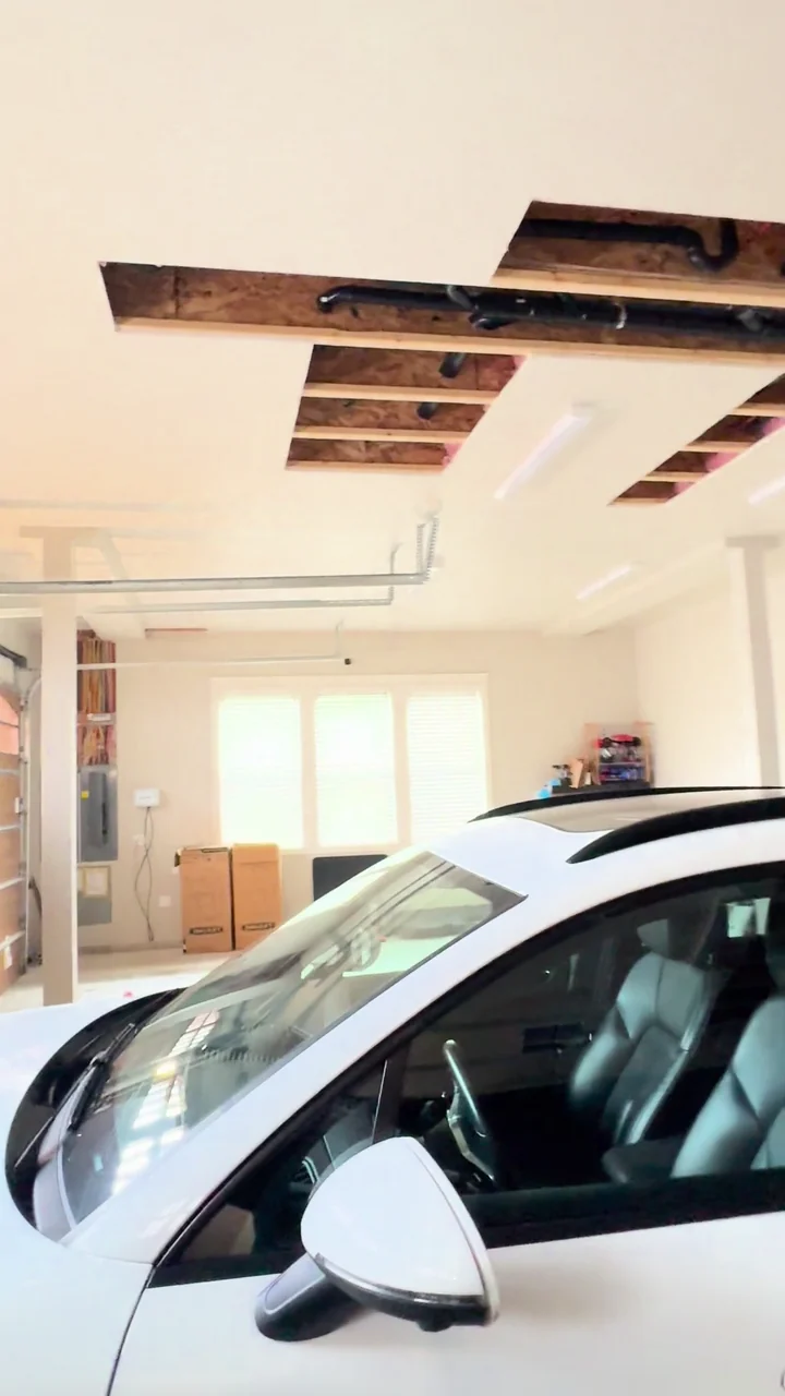 Open ceiling sections and protective sheeting in a garage before patching.