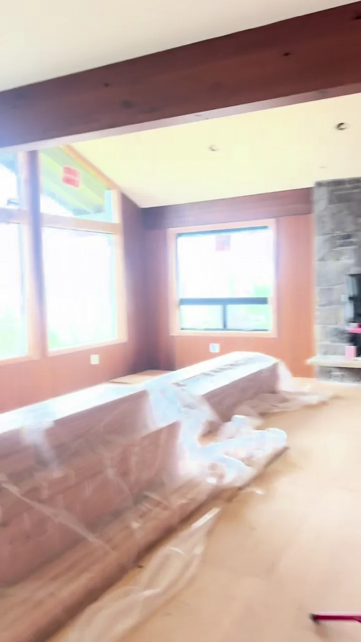 Finished ceiling surfaces around wood beams, with furnishings and floors covered during remodeling.