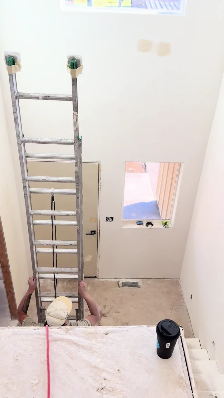 A walk through smooth drywall walls and doorways around a stairwell before trim and flooring are installed.