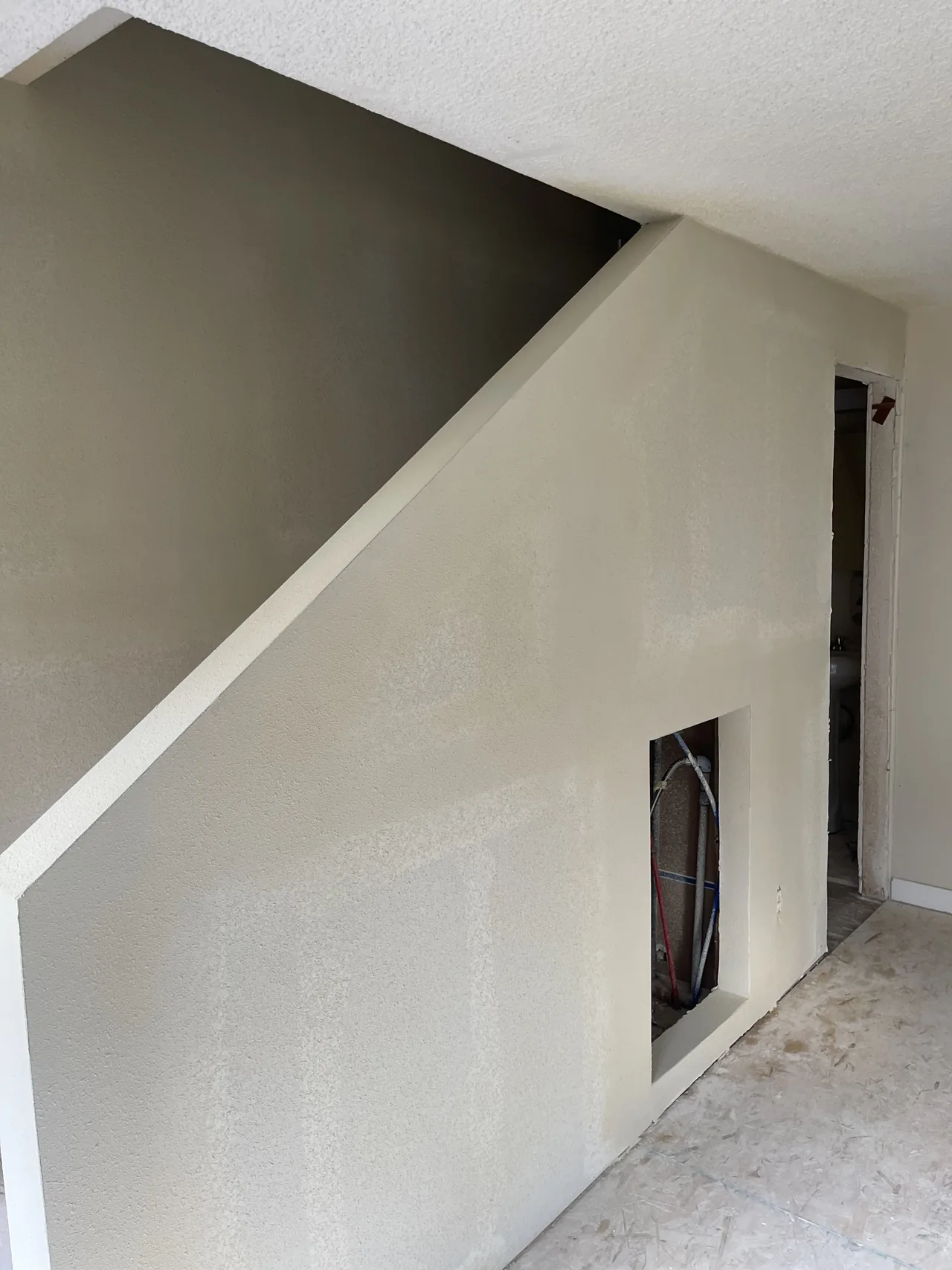 Drywall installation and taped joints following the slope of a staircase wall.