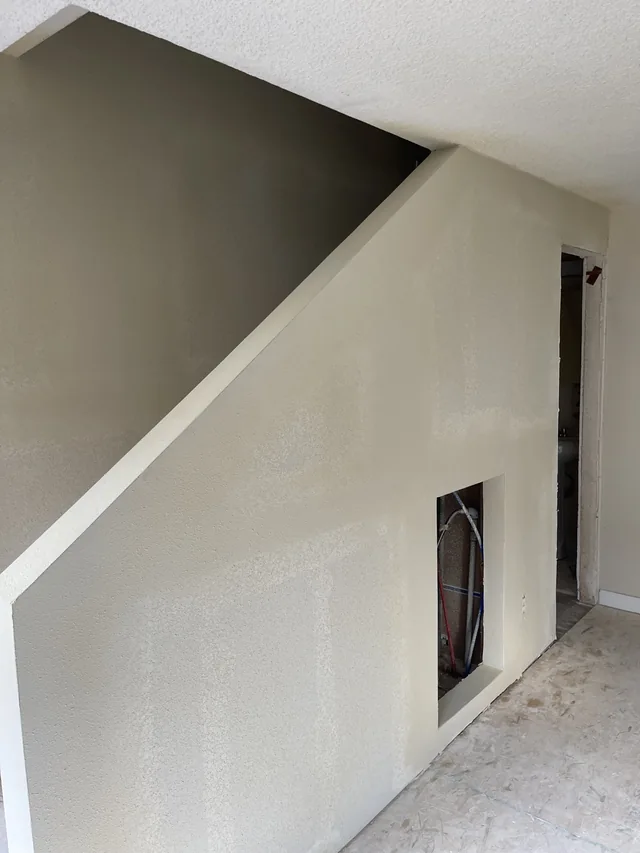 Drywall installed and taped along the sloped wall of a staircase.