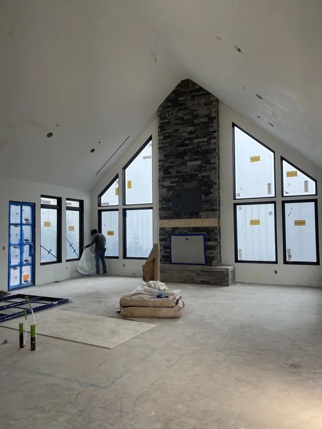 Altus drywall around a vaulted ceiling, tall windows and a stone fireplace.