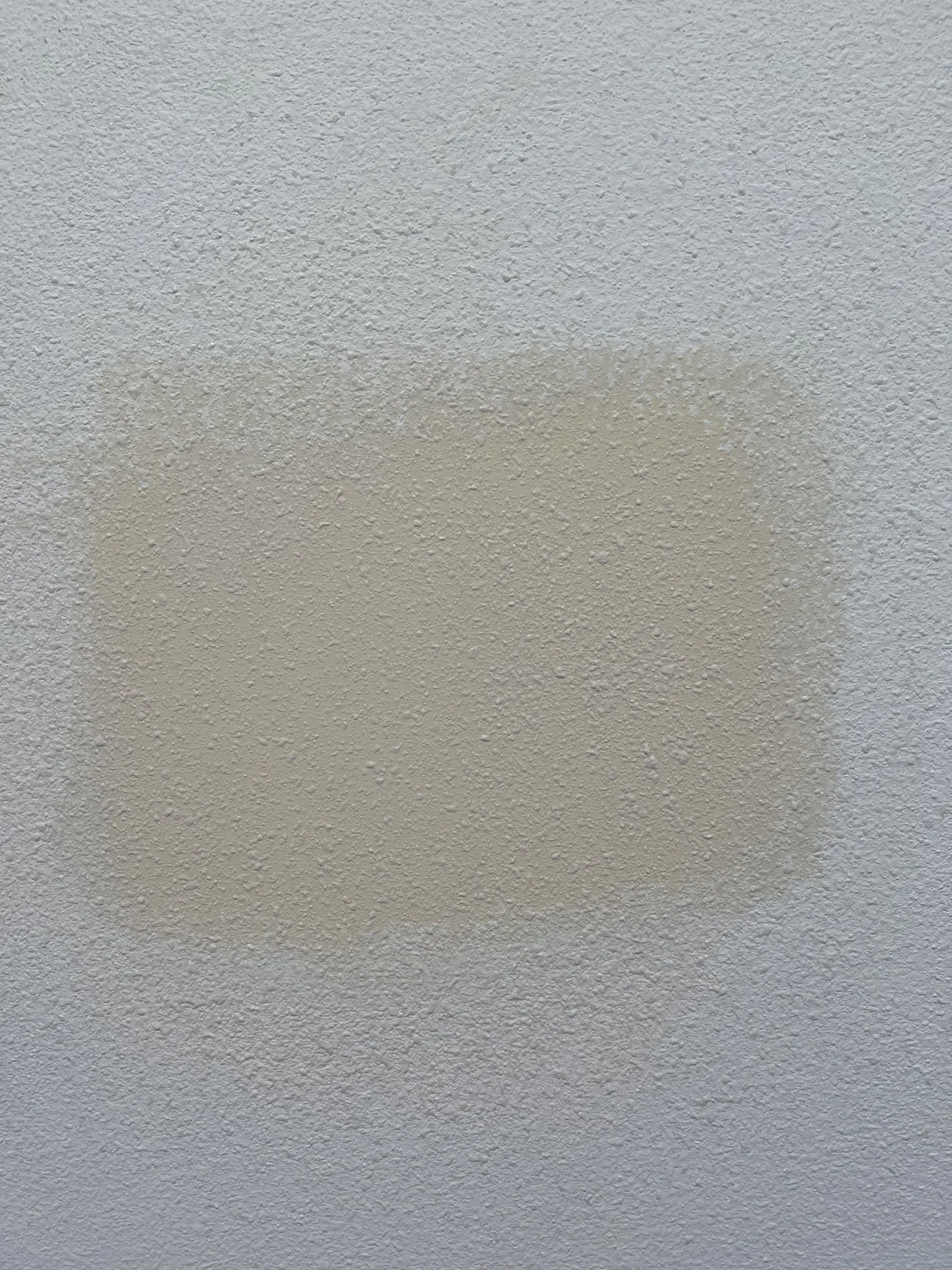 Drywall repair patch feathered into the surrounding textured wall.