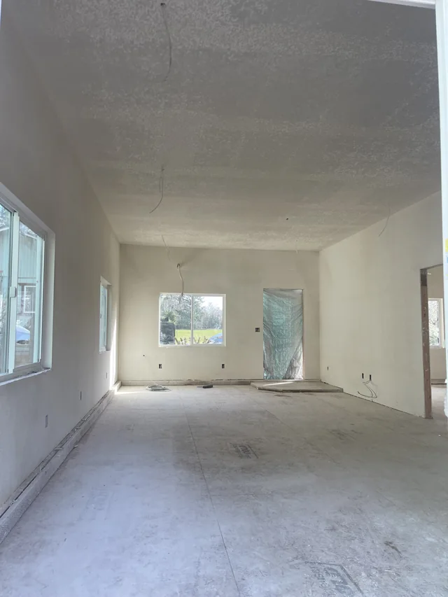 Finished drywall surfaces in a bright room with multiple windows.